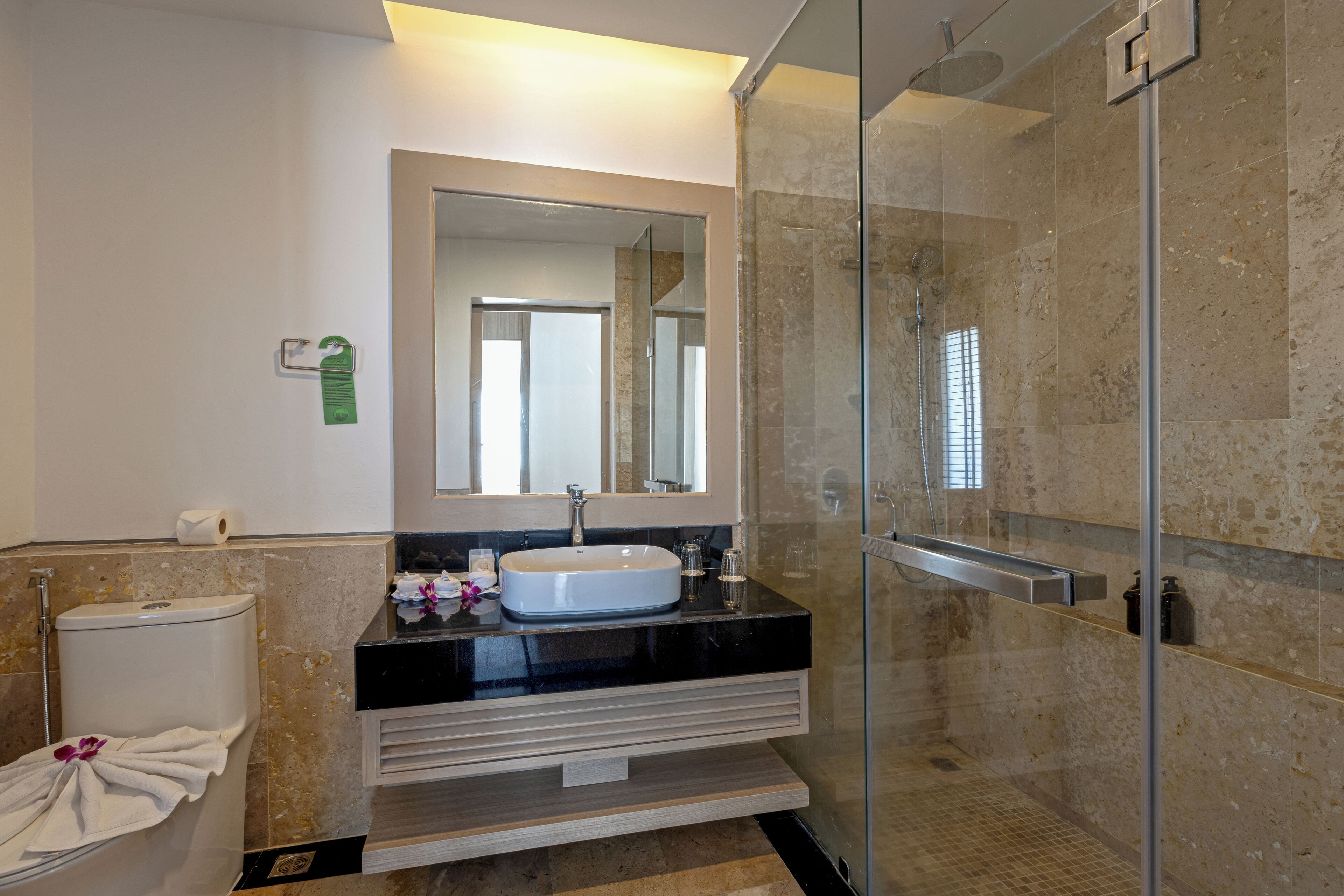 Une salle de bain moderne avec une douche à parois de verre, un lavabo blanc et un grand miroir.