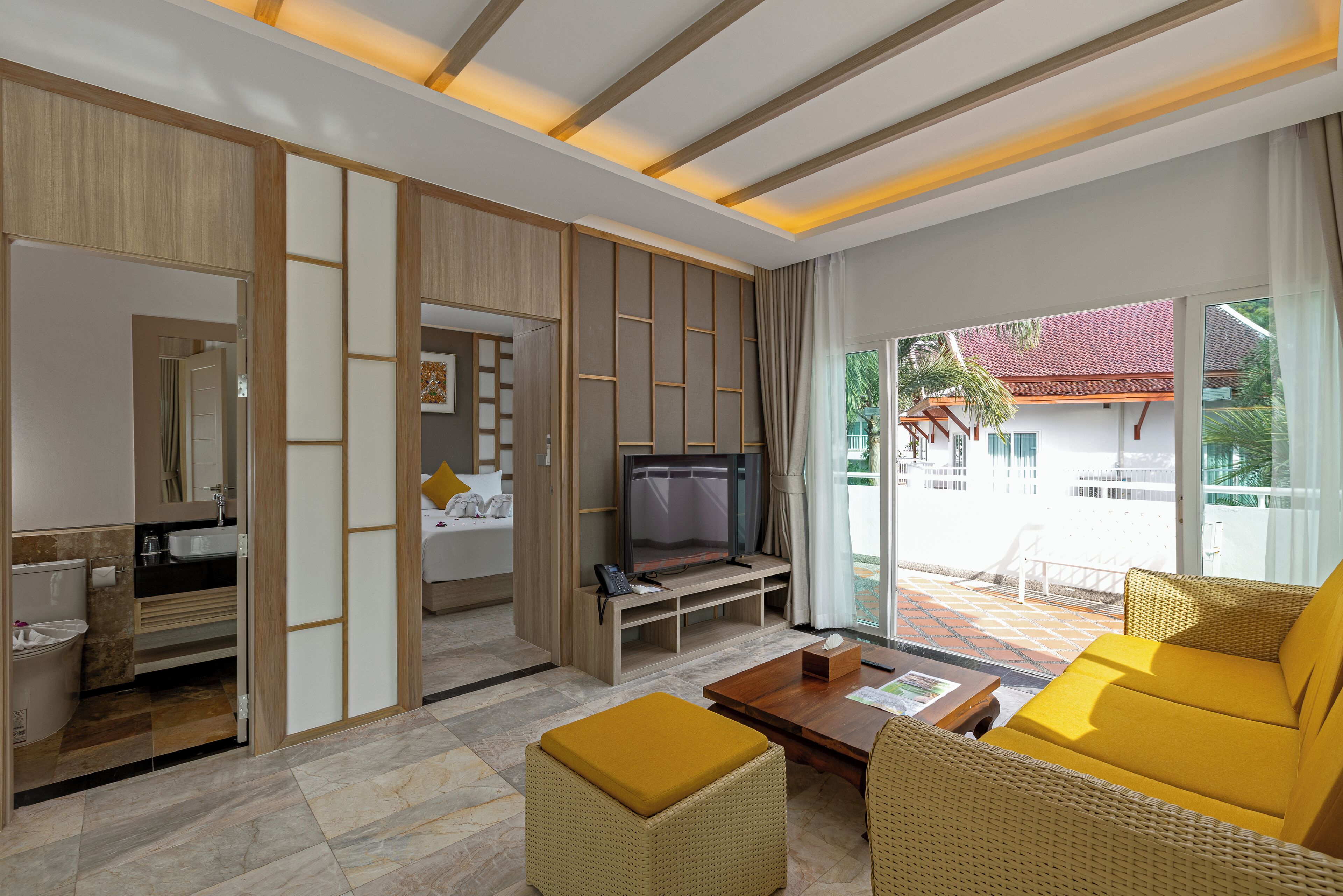 A modern hotel room with a TV, sofa, and dining table.