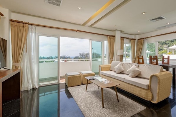 A modern living room with a sofa, coffee table, and a view of the outdoors. - Phunawa Resort Karon Beach Phuket (Karon)