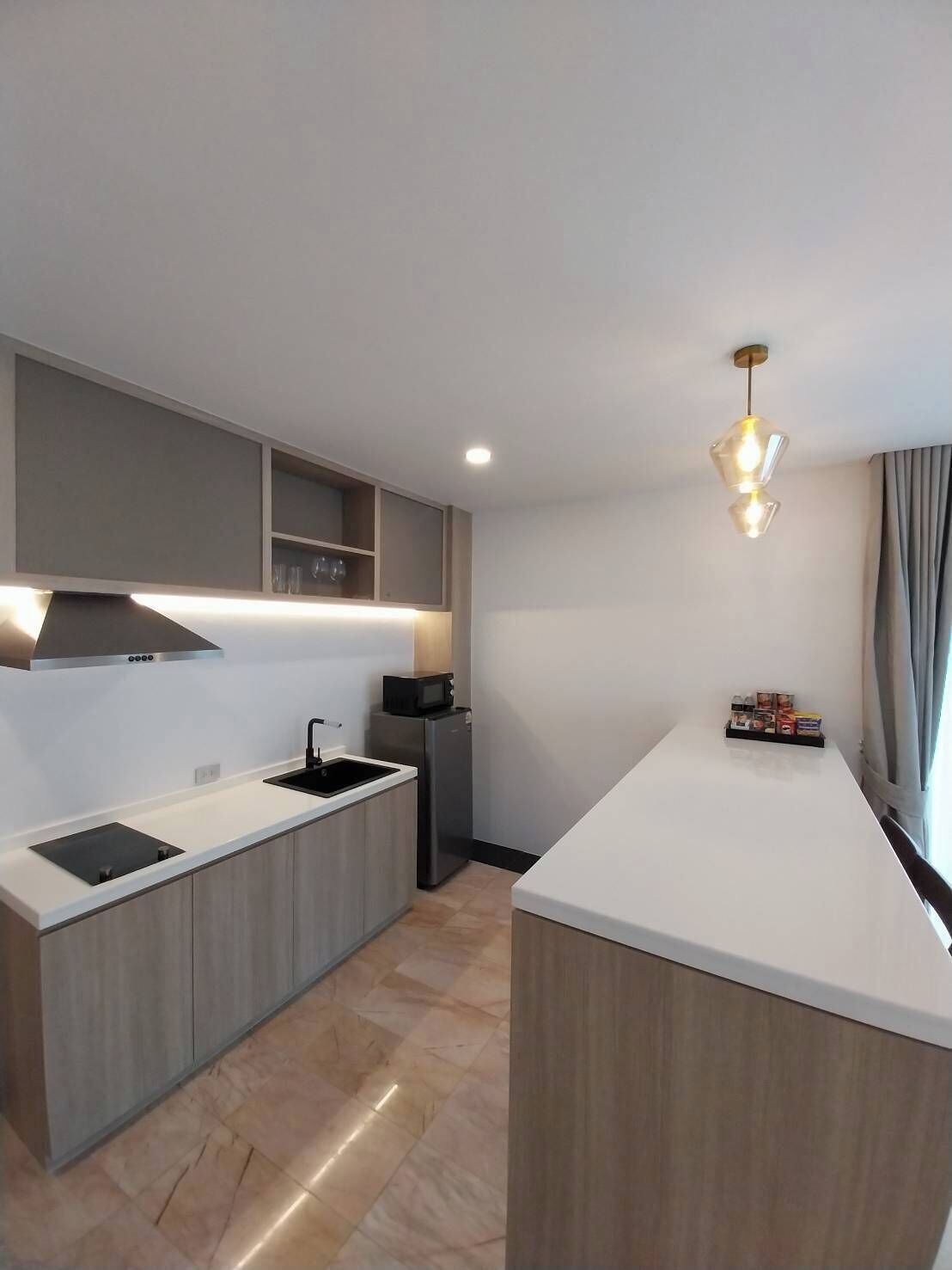 A modern kitchen with a central island, built-in cabinets, a microwave, and a stainless steel range hood.