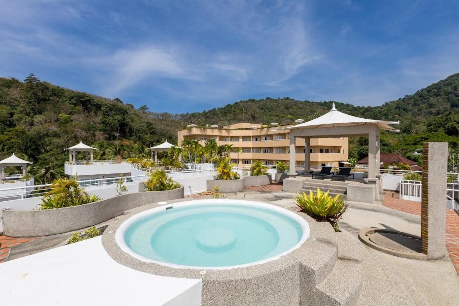 A rooftop pool with a clear view of a hotel and surrounding hills.