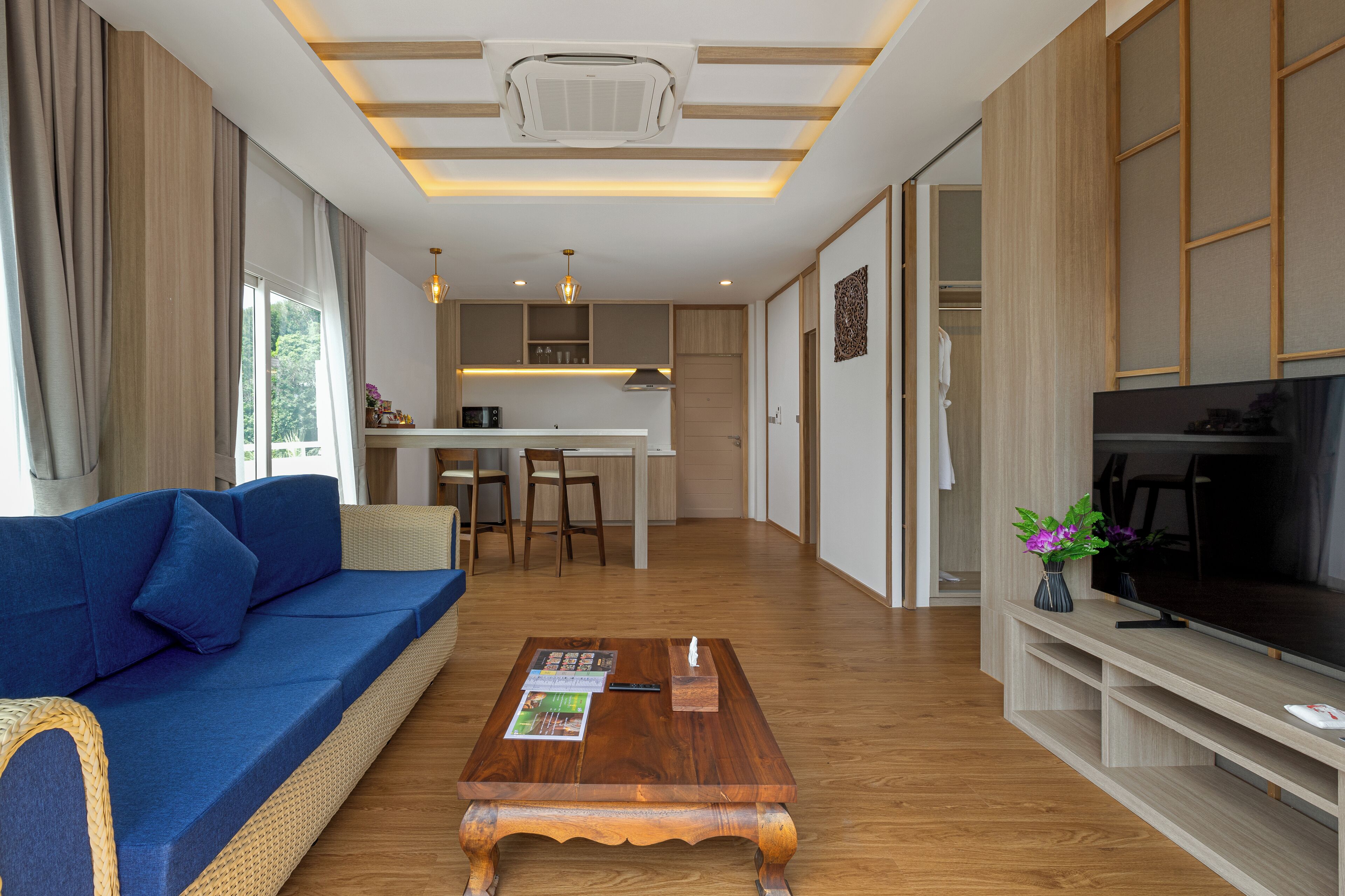 A modern living room with a blue sofa, wooden coffee table, and a TV on a wooden stand.