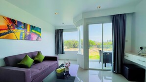 A modern living room with a purple sofa, a glass coffee table, and a large abstract painting. - Grand Sunset Hotel Phuket (Karon)