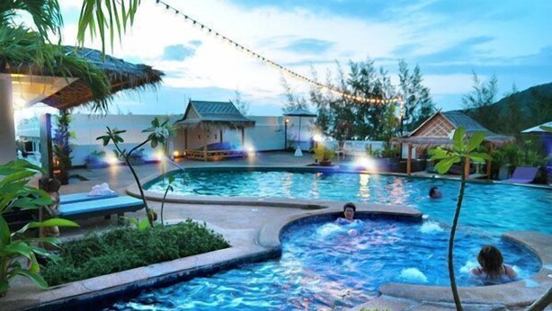 A swimming pool area with a hot tub, lounge chairs, and a thatched-roof structure. - Phuket Heritage Hotel (Karon)