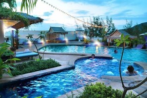 A swimming pool area with a hot tub, lounge chairs, and a thatched-roof structure. - Phuket Heritage Hotel (Karon)