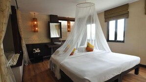 A bedroom with a bed, bedside table, and a mirror. - Phuket Heritage Hotel (Karon)