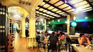 A restaurant with wooden flooring and tables, featuring a covered outdoor seating area with green lighting. - Phuket Heritage Hotel (Karon)