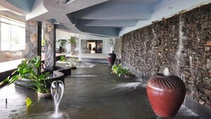 A lobby with a stone wall, a water feature, and potted plants. - Phuket Heritage Hotel (Karon)