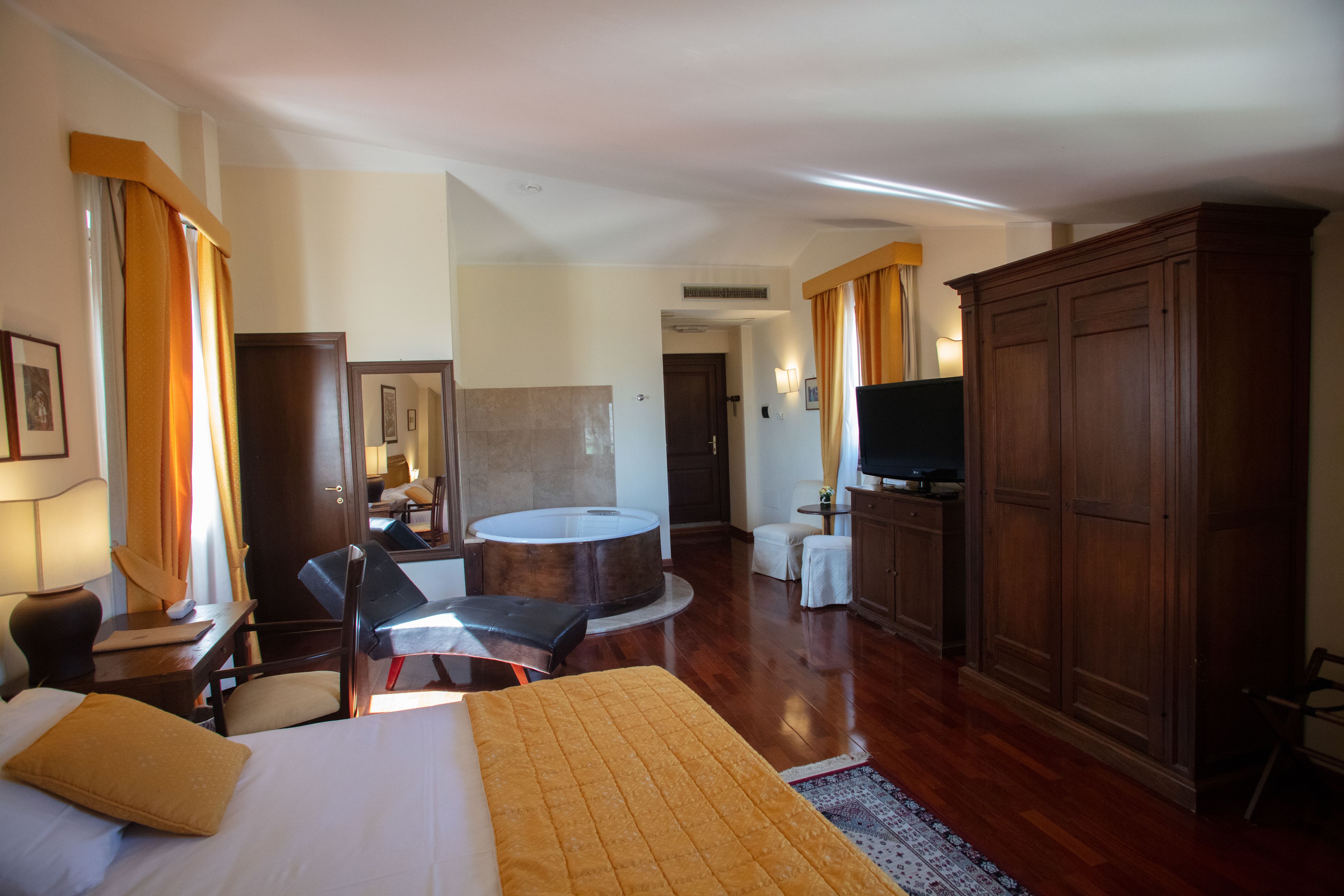 Una habitación de hotel con cama, escritorio, silla, mesa redonda, televisor y armario.