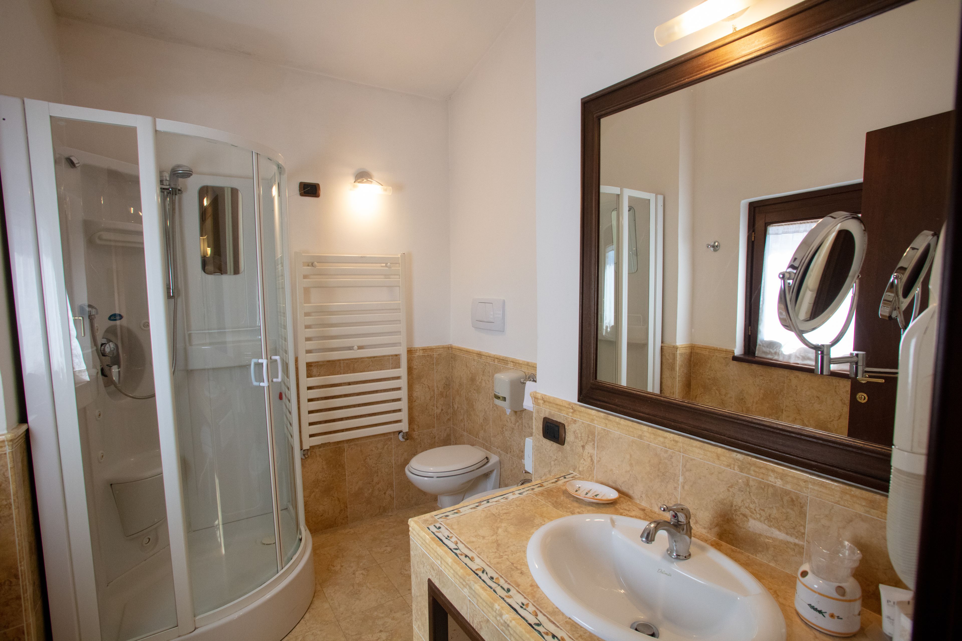 A bathroom with a glass-enclosed shower, a toilet, a sink with a mirror, and a towel rack.