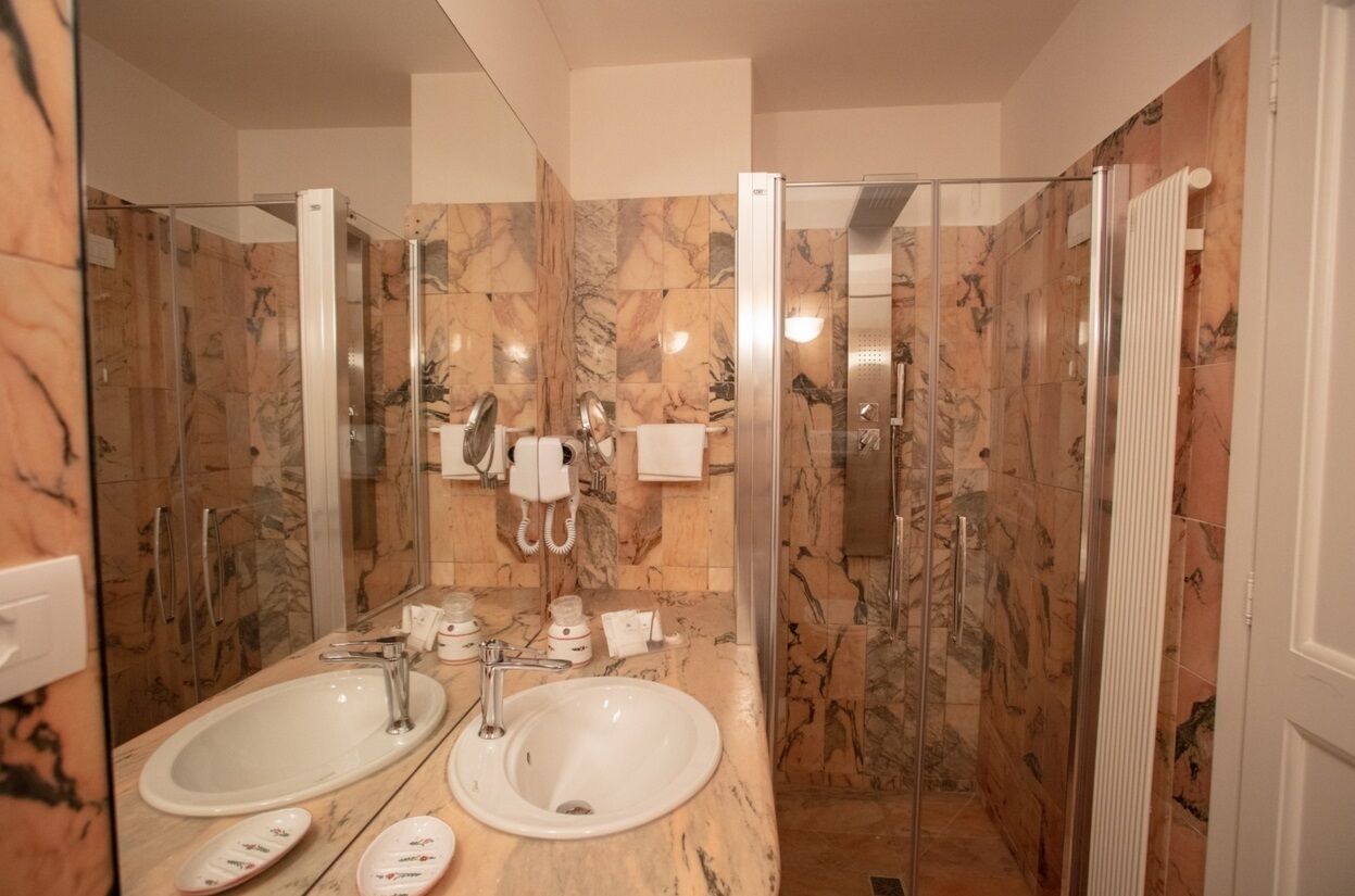 Ein Badezimmer mit zwei Waschbecken, einem Spiegel und einer Duschkabine aus Glas.