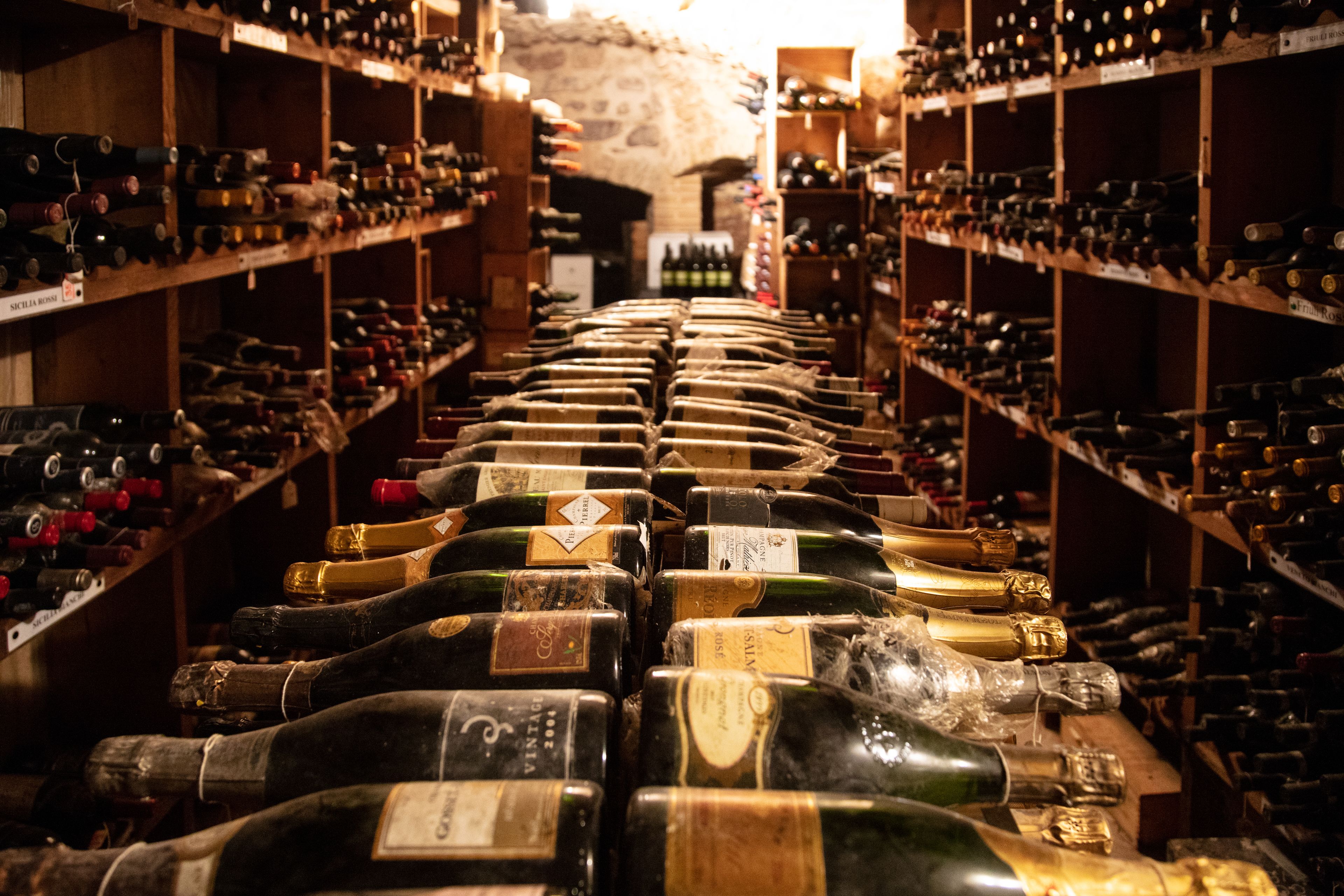 A wine cellar with rows of wine bottles on shelves.