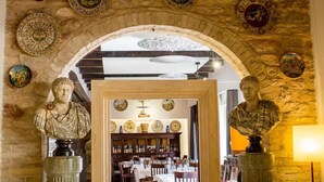 An arched doorway with classical bust sculptures on either side, leading to a dining area with tables and chairs. - Hotel Ristorante La Bastiglia (Spello)