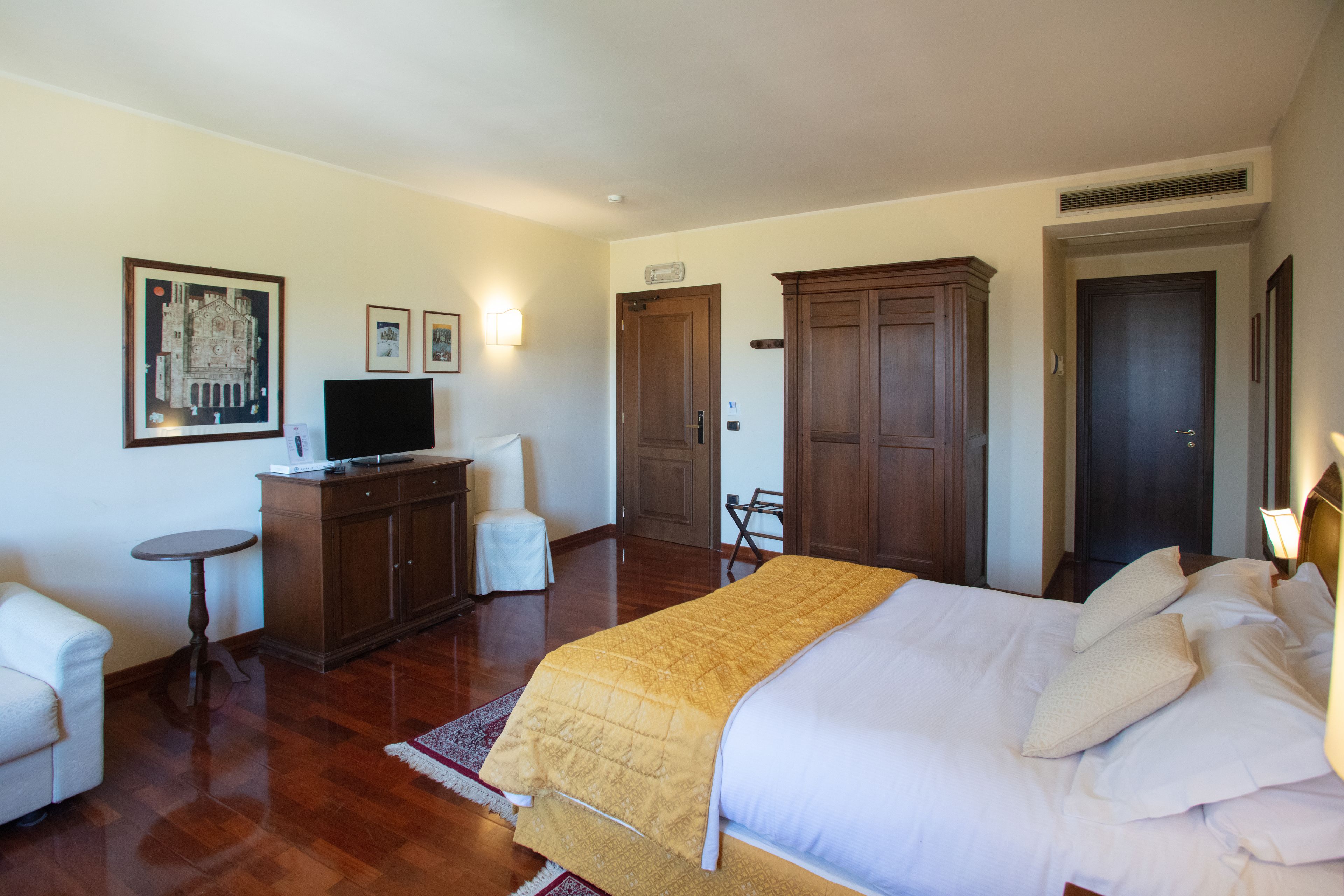 A hotel room with a bed, a desk, a chair, and a television.