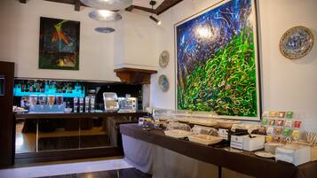 A bar area with a counter, various food items, and a large abstract painting on the wall.