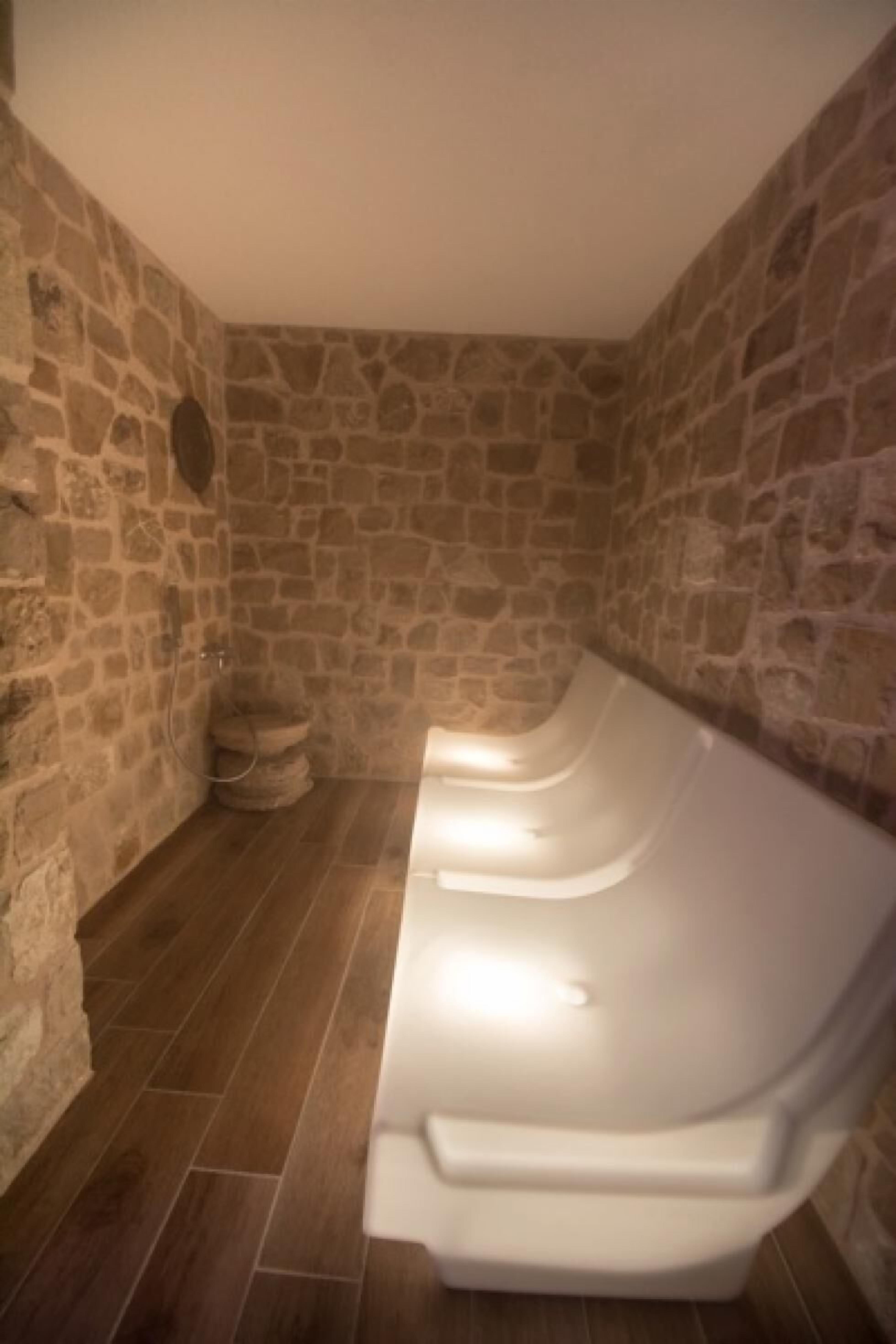 Una habitación con paredes de piedra y una fila de bancos blancos.