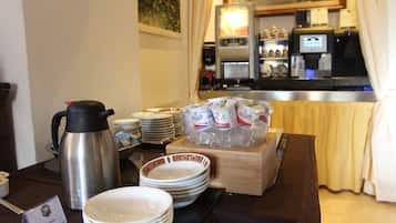 Un buffet della colazione con piatti, ciotole, una caffettiera e un frigorifero sullo sfondo.