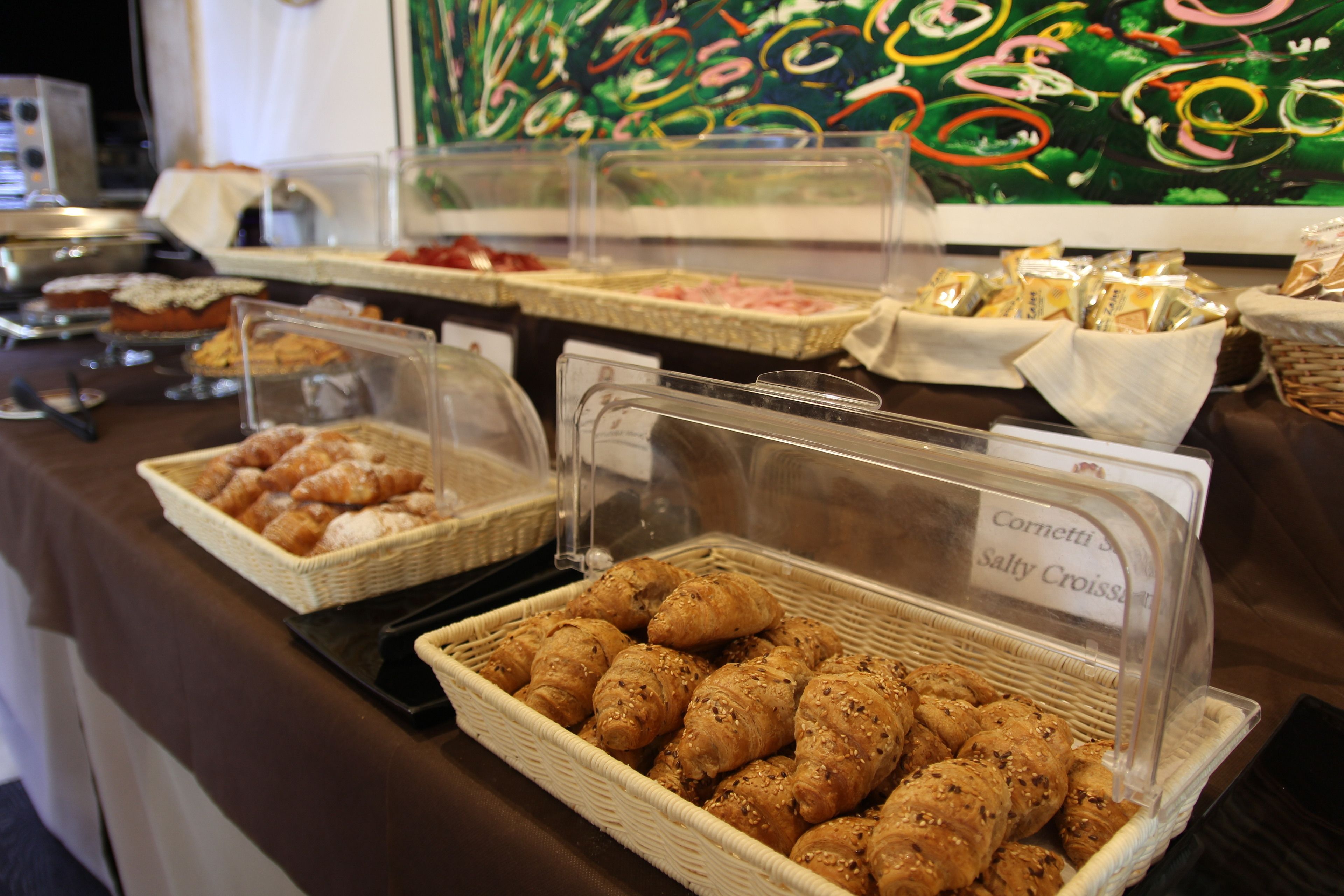A buffet with various food items, including baskets of croissants and other baked goods.