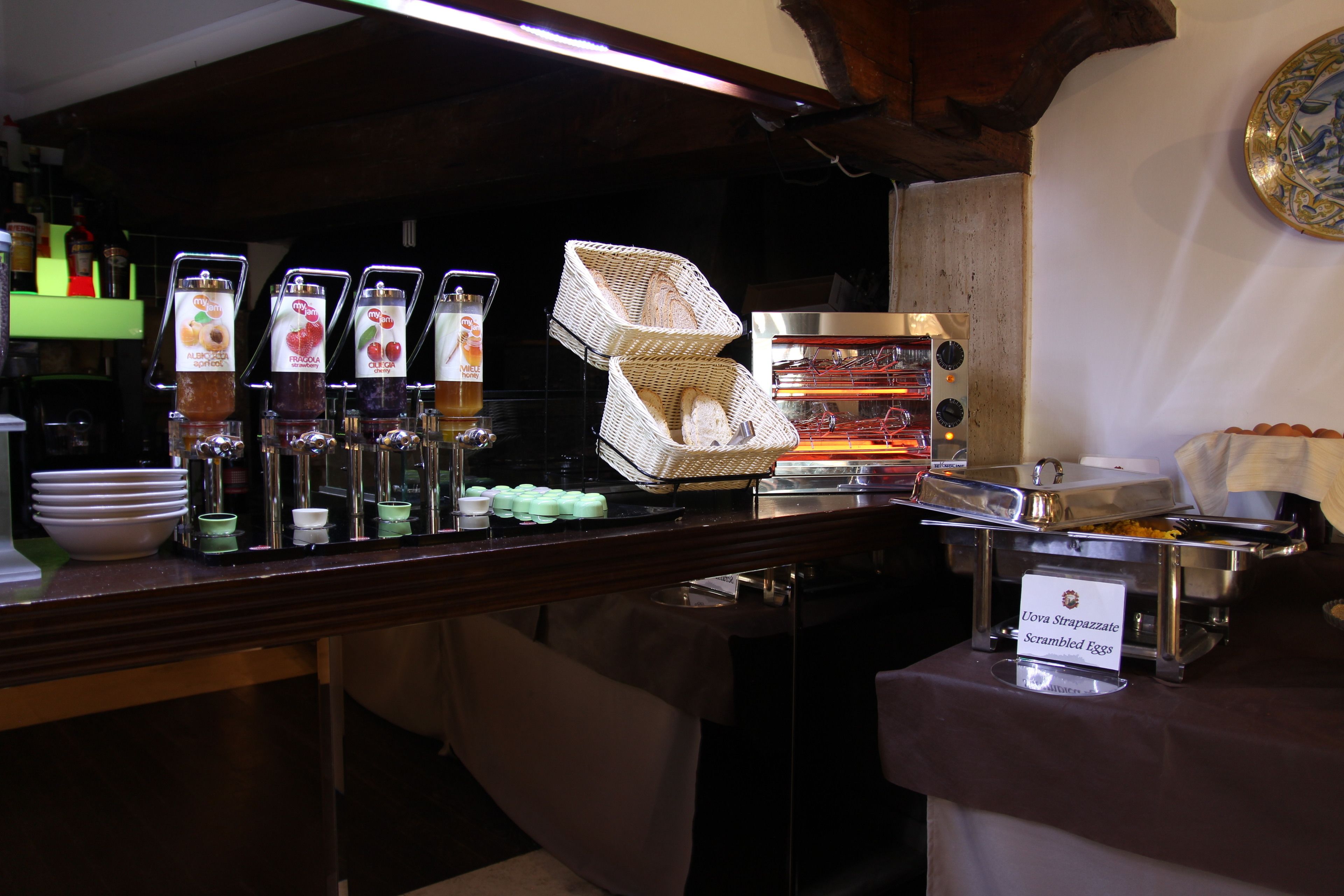 A buffet setup with various food items and a sign indicating 'Uva Strappazzate Scrambled Eggs'.