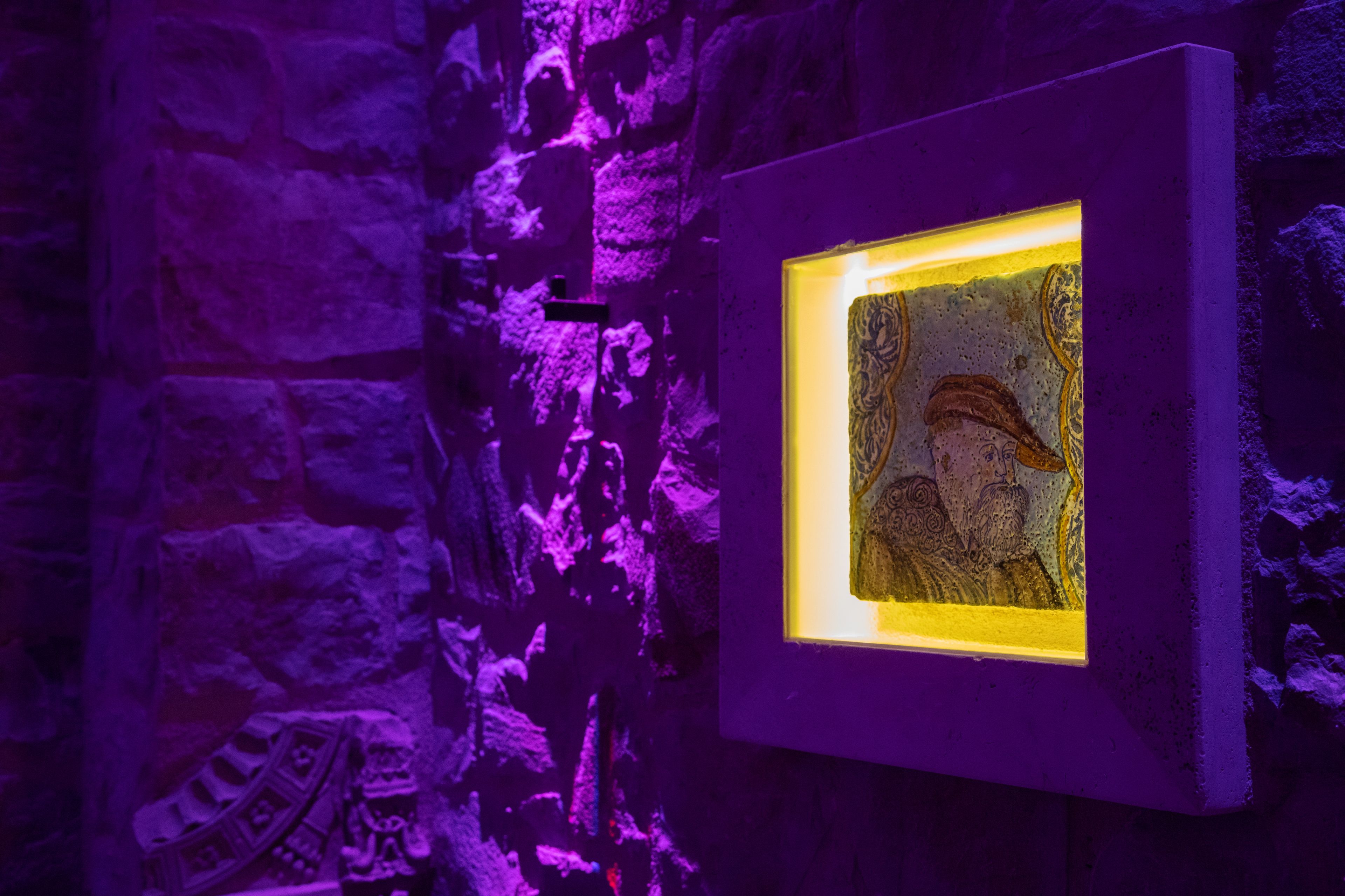 Una obra de arte enmarco en una pared de piedra de tono morado.
