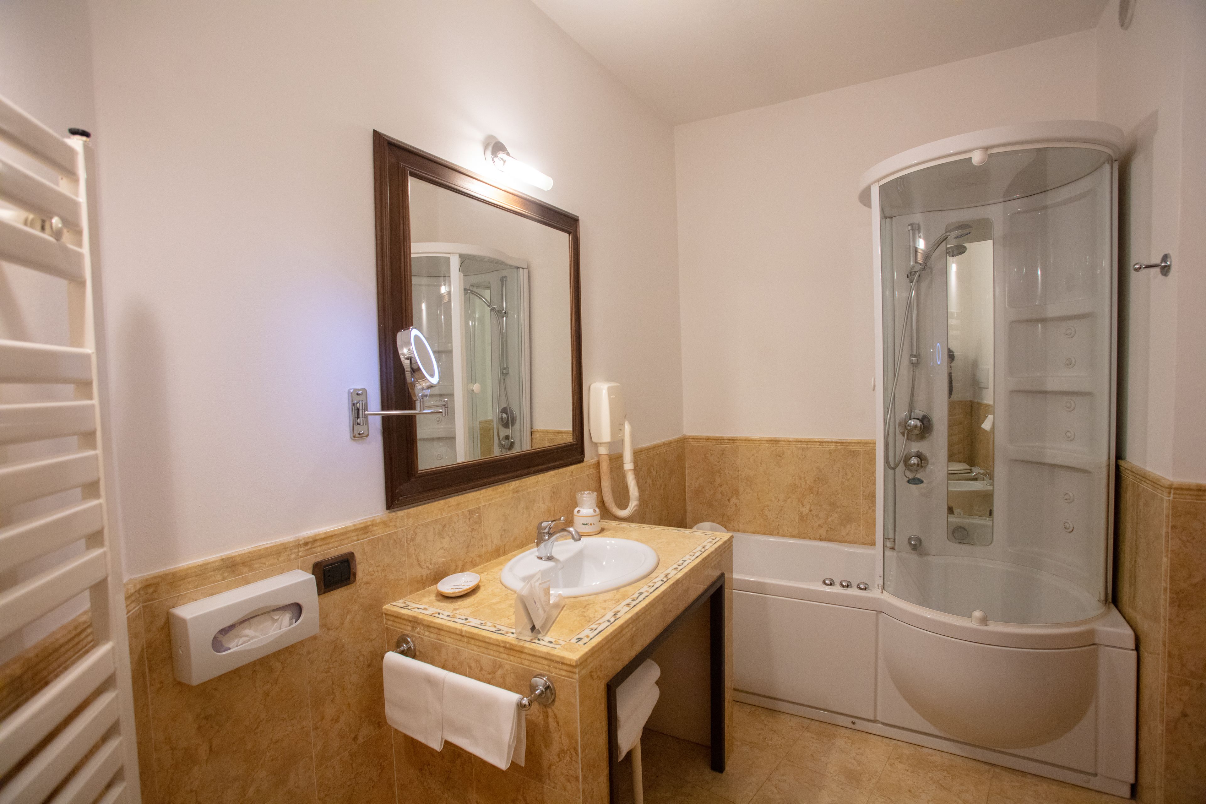 Un baño con lavamanos, espejo, toallero y cabina de ducha.