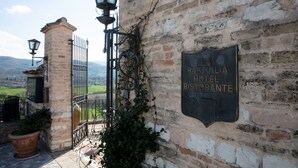 A rustic stone wall with a sign for La Basiglia Hotel Ristorante. - Hotel Ristorante La Bastiglia (Spello)