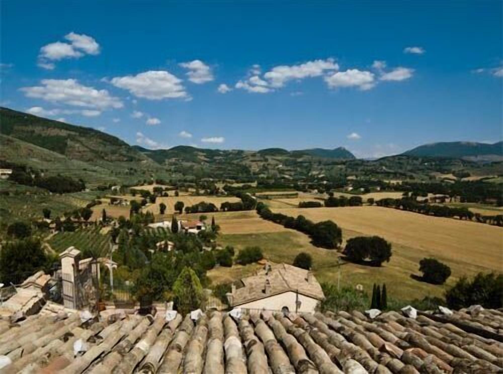 A rural landscape with rolling hills, a clear sky, and a traditional building with a tiled roof.