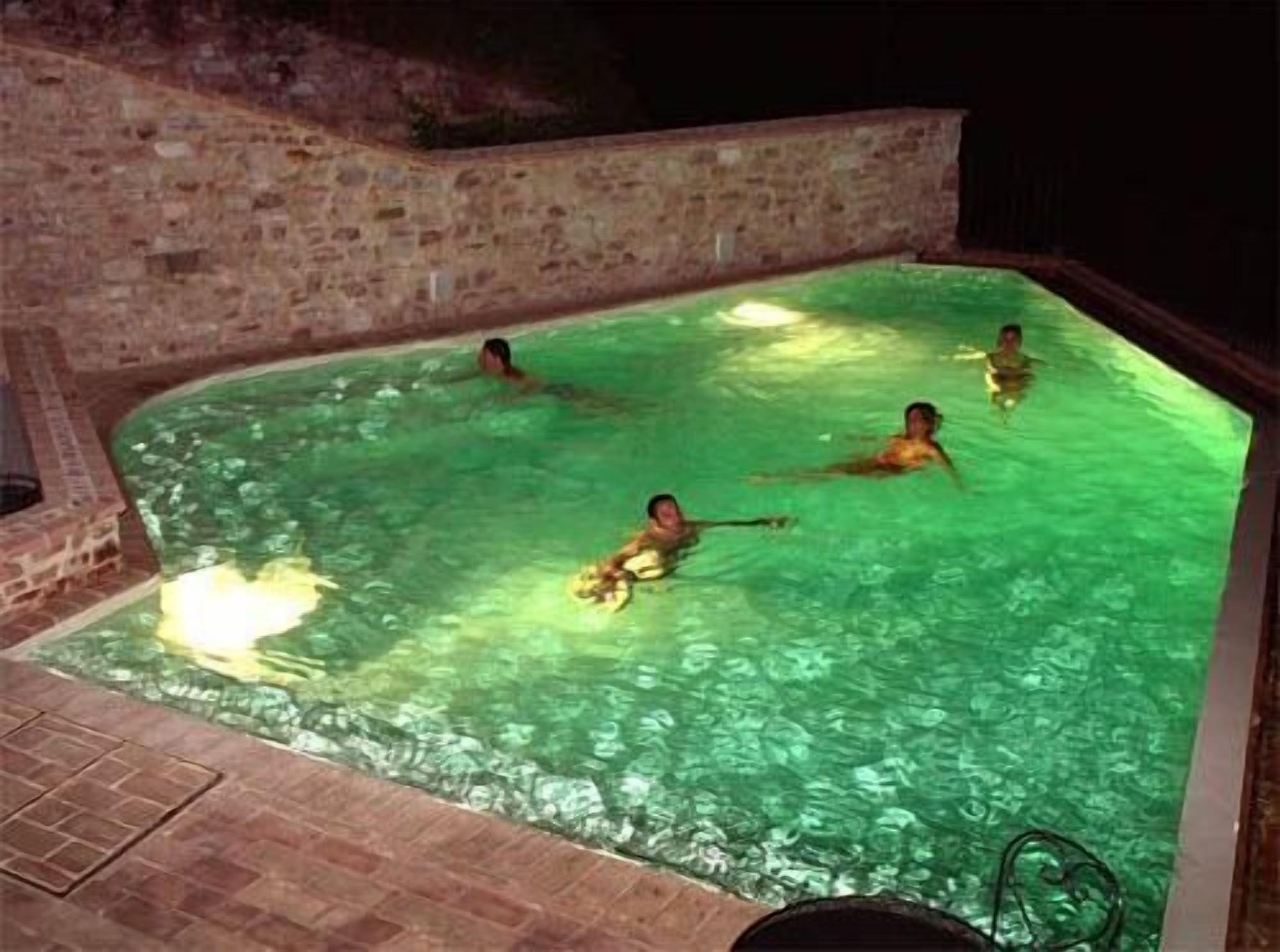 A swimming pool with a stone wall and tiled floor.