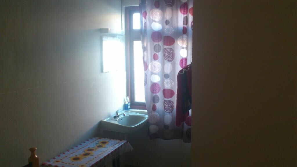 Un bagno piccolo con un lavandino, una finestra e una tenda.