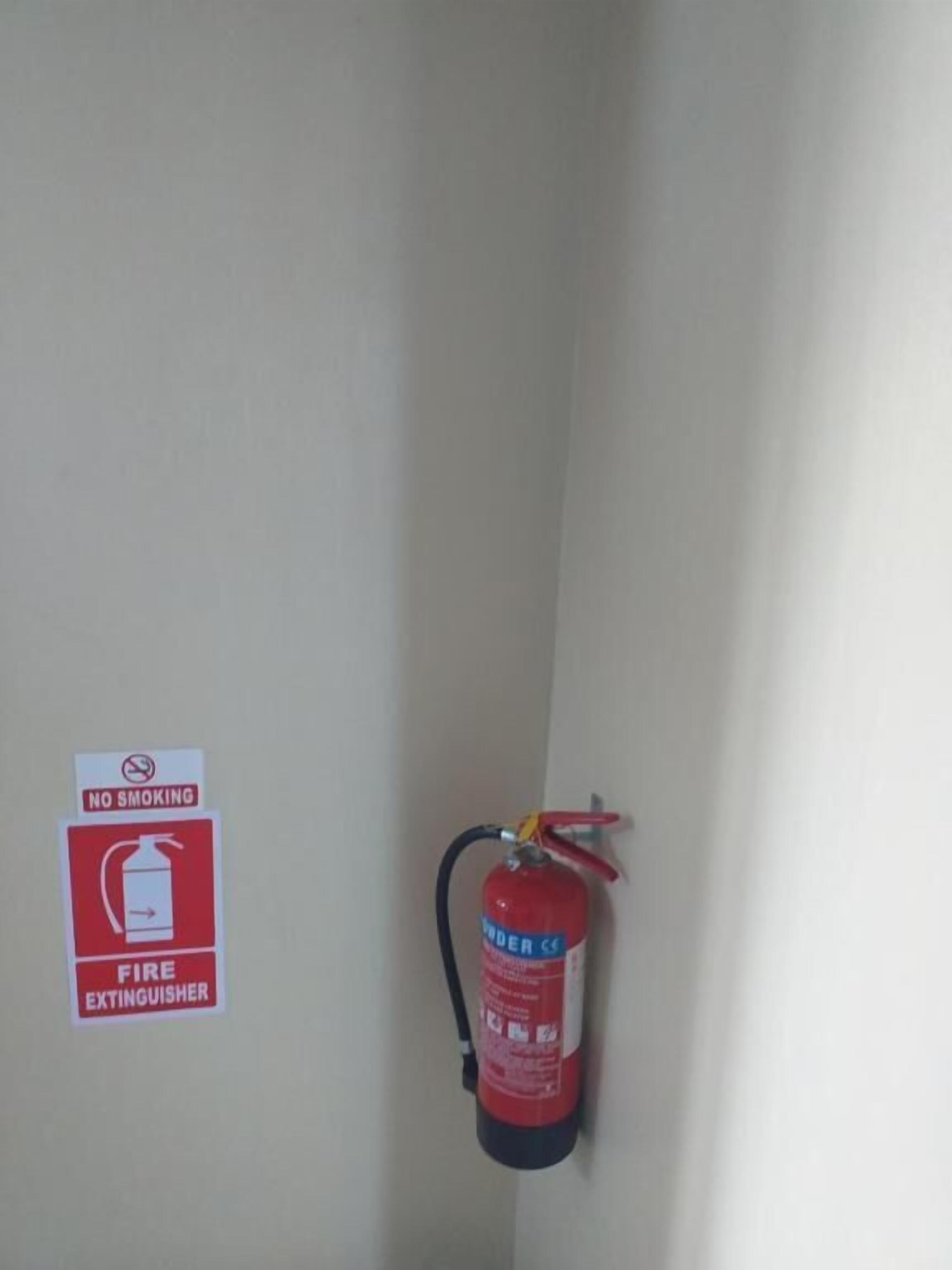 A wall-mounted fire extinguisher and a no-smoking sign in a room corner.