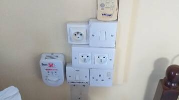 A wall-mounted electrical panel with multiple sockets and a Pacific brand thermostat.