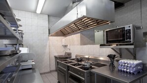 A commercial kitchen with stainless steel appliances, a microwave, and a stack of eggs.
