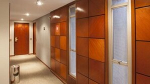 A hallway with wooden paneling, a trash bin, and a door at the end.