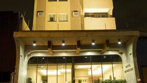 A multi-story hotel with a modern design, featuring a prominent staircase leading to the entrance, and a sign indicating the name "HOTEL MONCLOA".