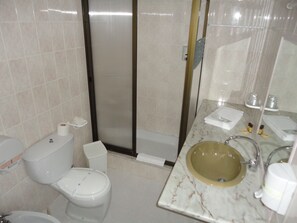 A bathroom with a toilet, a shower, and a sink.