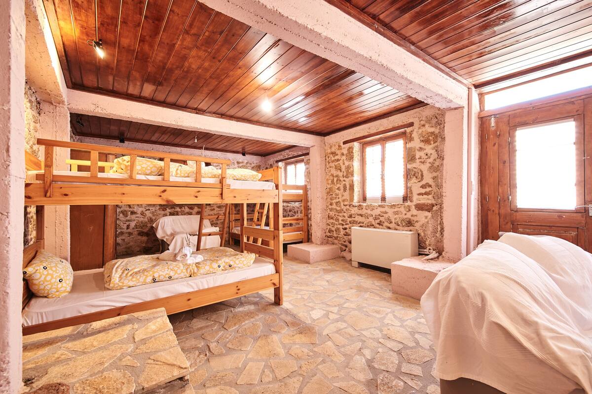 A rustic room with bunk beds, stone walls, and wooden beams.