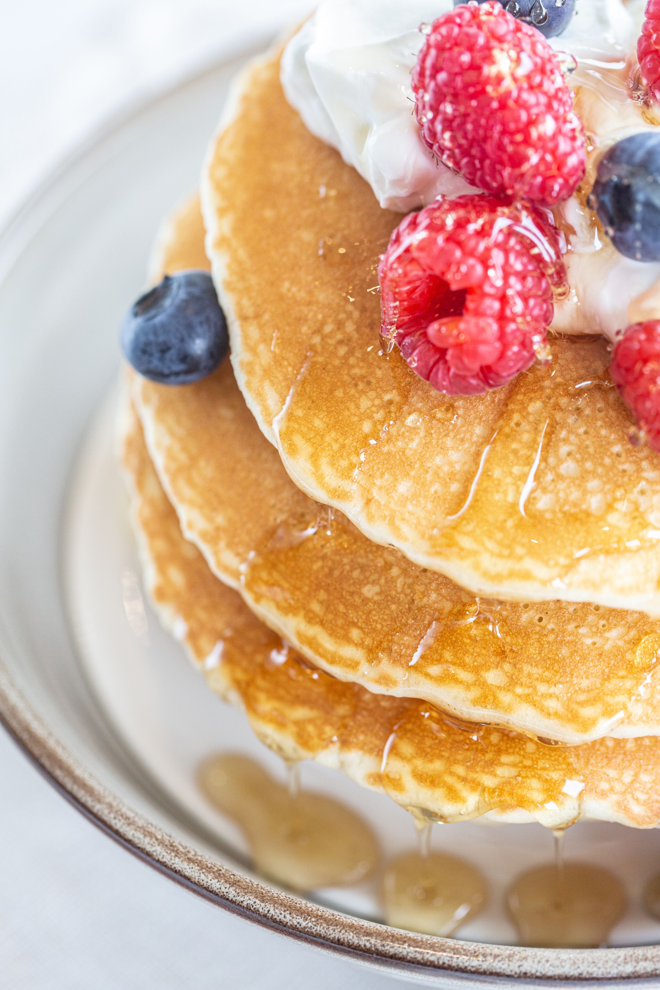 A stack of pancakes with berries and syrup.