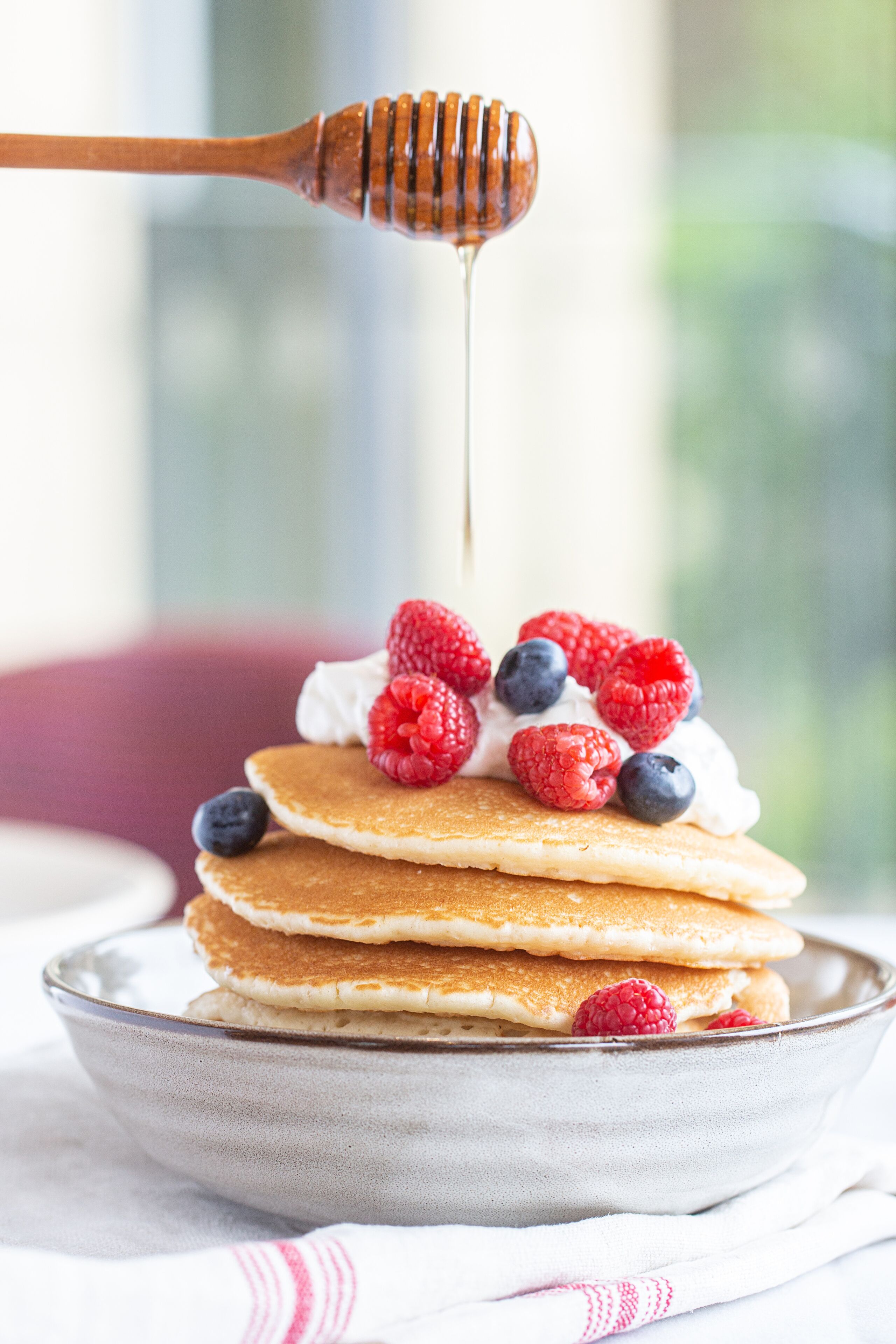 A stack of pancakes with berries and honey.