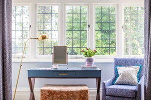 A room with a desk, chair, and a window with a view of trees.
