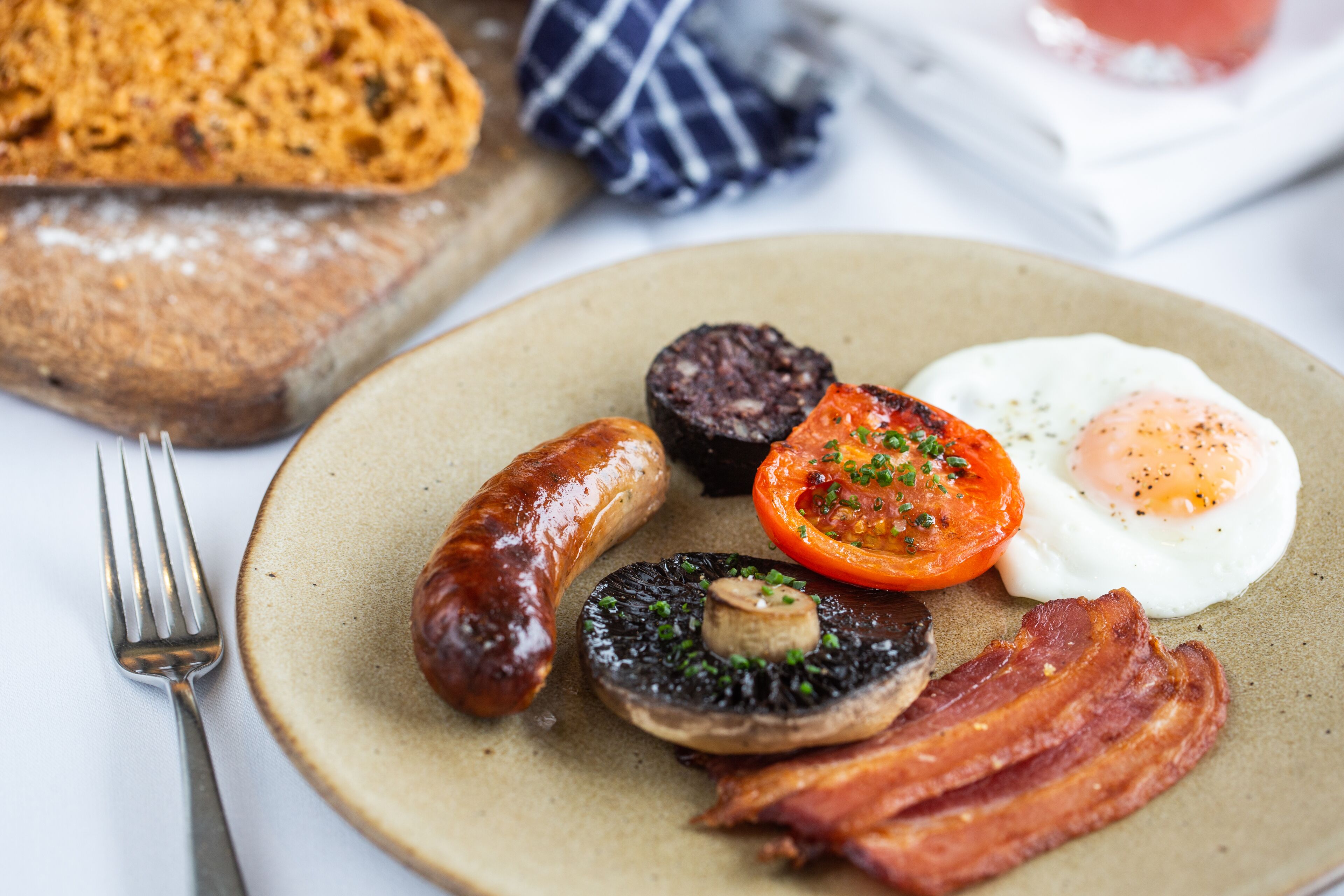 A plate of breakfast food including sausages, eggs, tomatoes, mushrooms, and bacon.