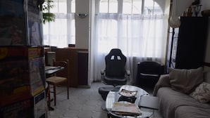 Una sala de estar con sofá, mesa de centro, silla, escritorio y ventana con cortinas.