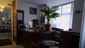 Un área de bar acogedora con mostrador de madera, una planta en maceta y una mesa con sillas.