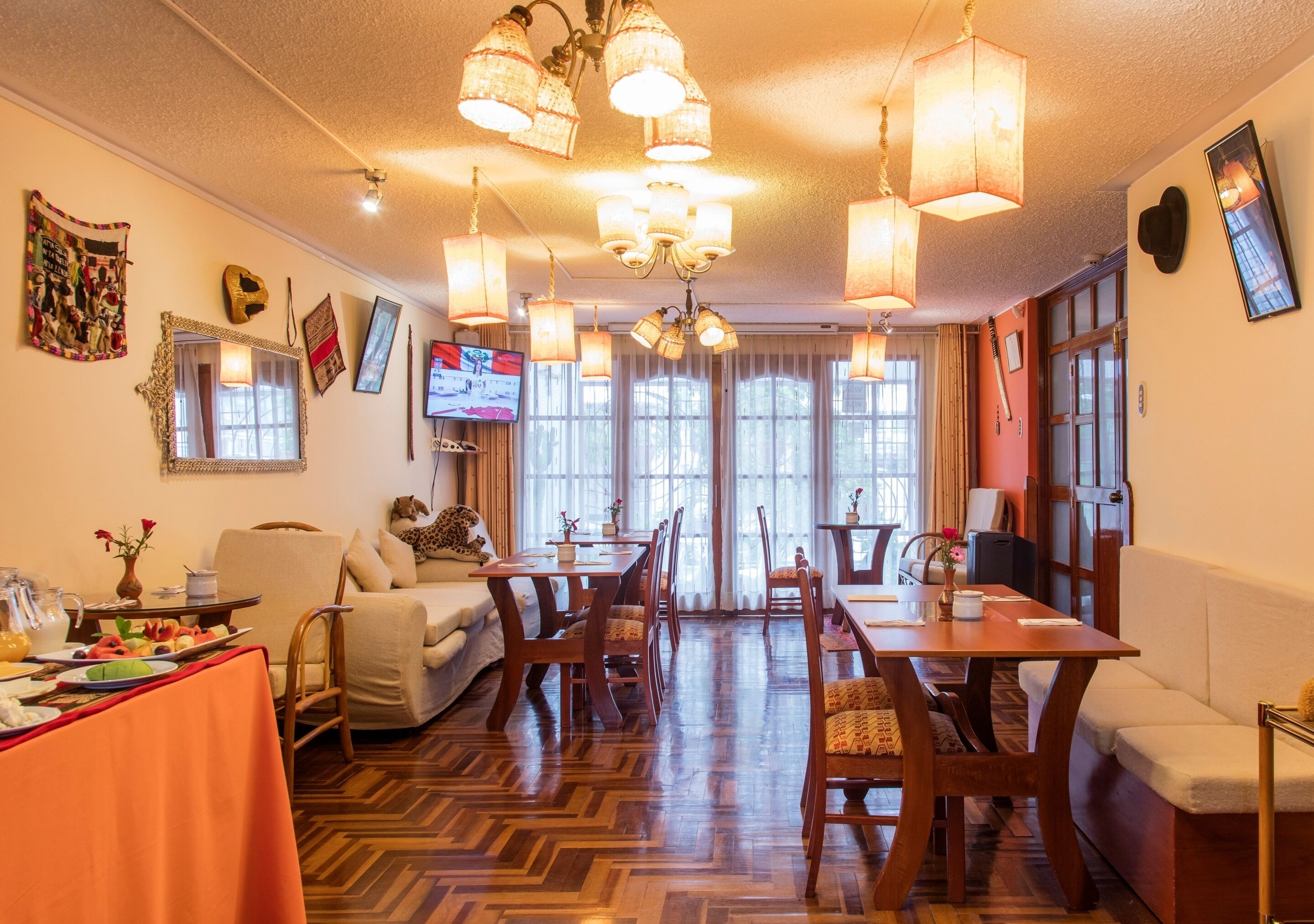 Un comedor con mesas y sillas de madera, un sofá y un televisor.