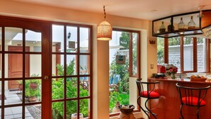 Una cocina amplia con ventanas grandes, una barra de madera y sillas rojas con cojines.