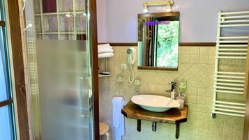 A bathroom with a glass shower enclosure, a wooden vanity with a sink, a towel rack, and a mirror.