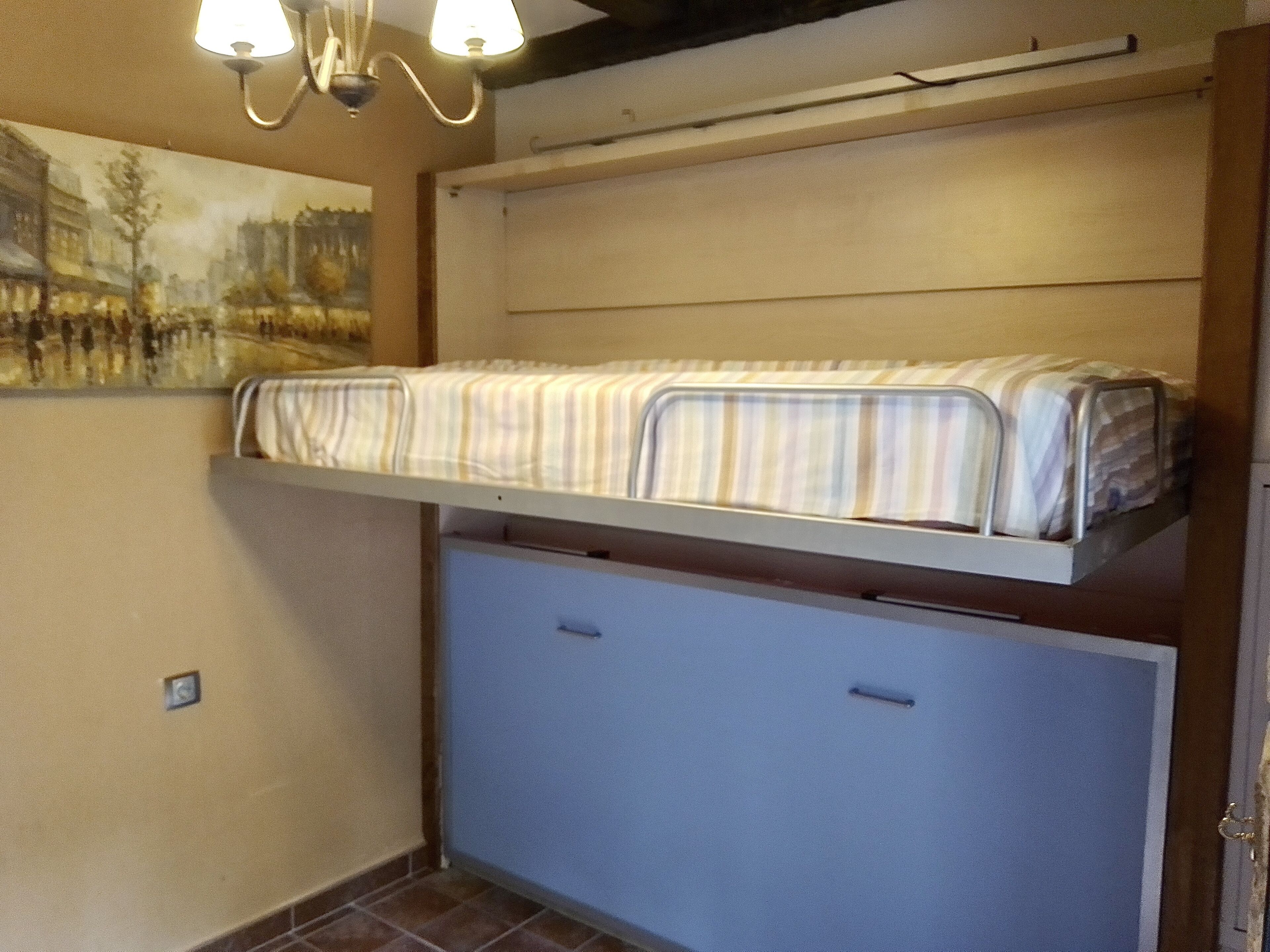 A compact room with a bunk bed, a small desk, and a wall-mounted shelf.