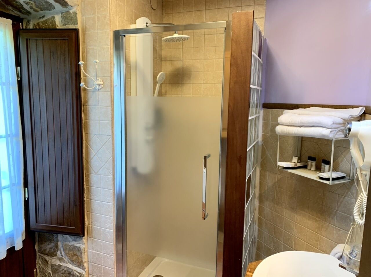 Un baño con ducha de vidrio, inodoro y perchero para toallas.