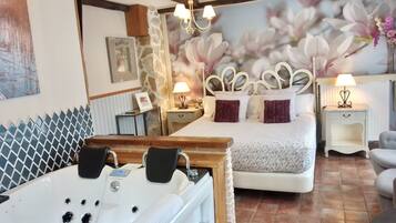 Un dormitorio con una cama grande, cabecera de madera, bañera blanca y un mural de flores en la pared.