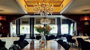 A formal dining room with a large wooden table, black chairs, and a central chandelier. - Hotel de Roode Leeuw (Terborg)