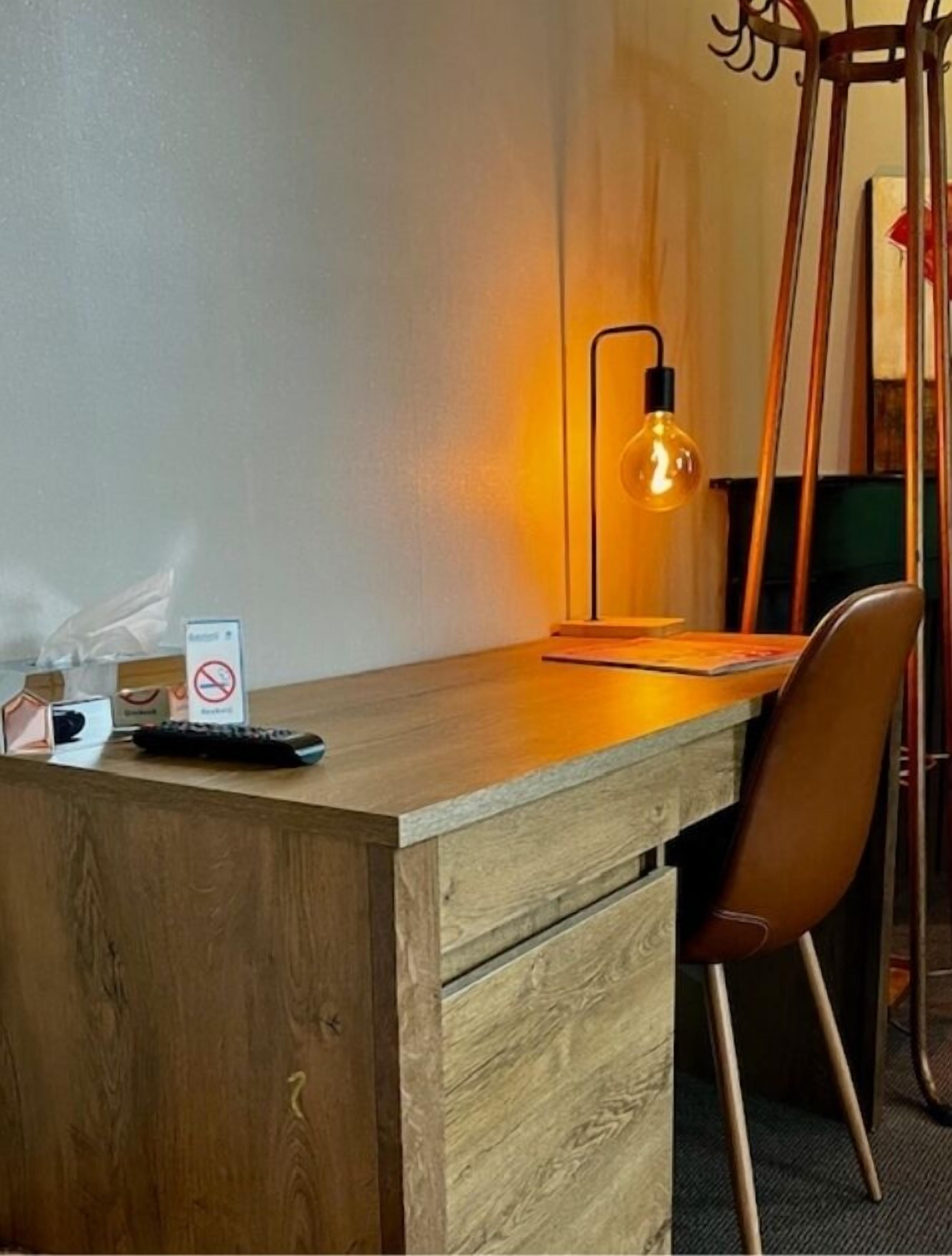 Un escritorio de madera con una lámpara, un cartel y un teclado.